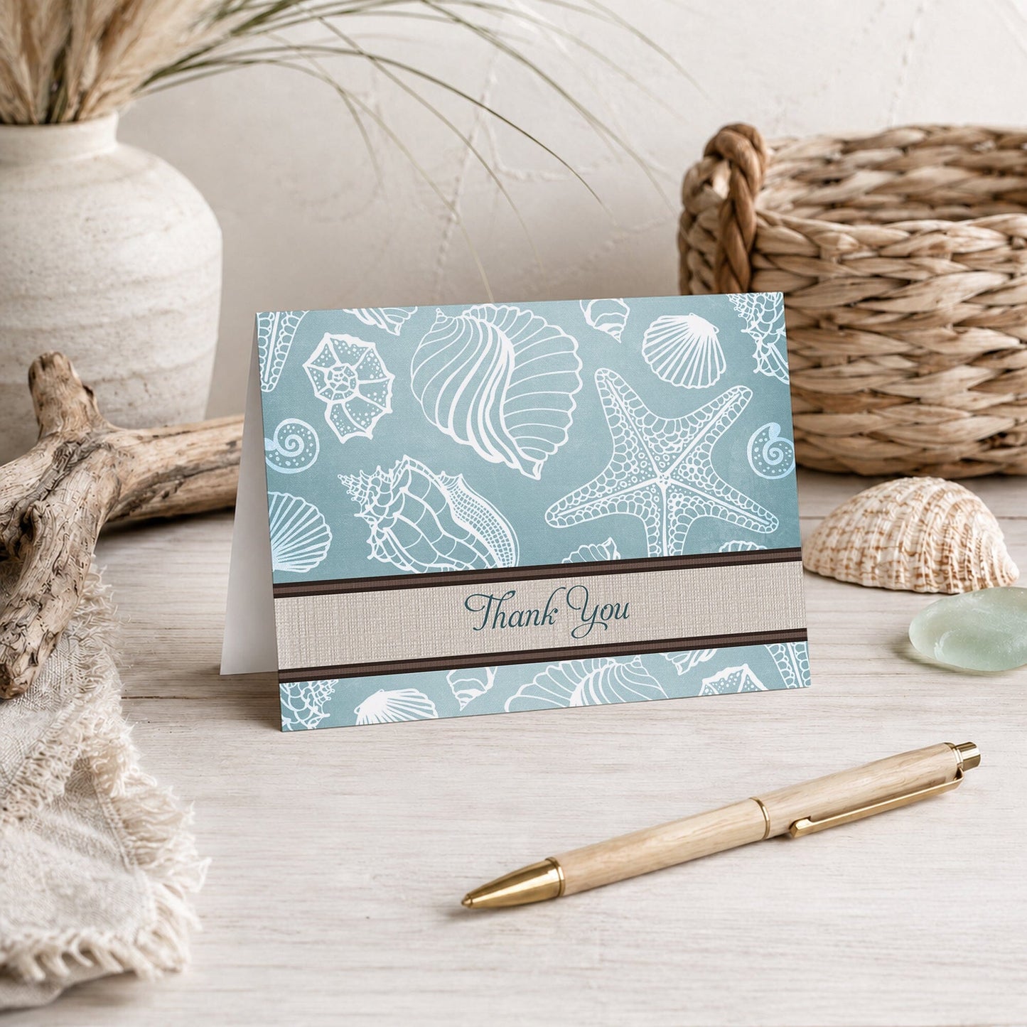 Rustic Beach Linen Seashell Thank You Card shown on a beach house tabletop with coastal decor and a pen.