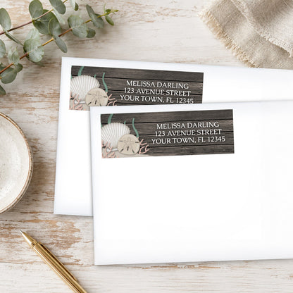 Rustic Beach Seashells and Wood Address Labels on white envelopes, shown on a wooden surface with plants and a pen.