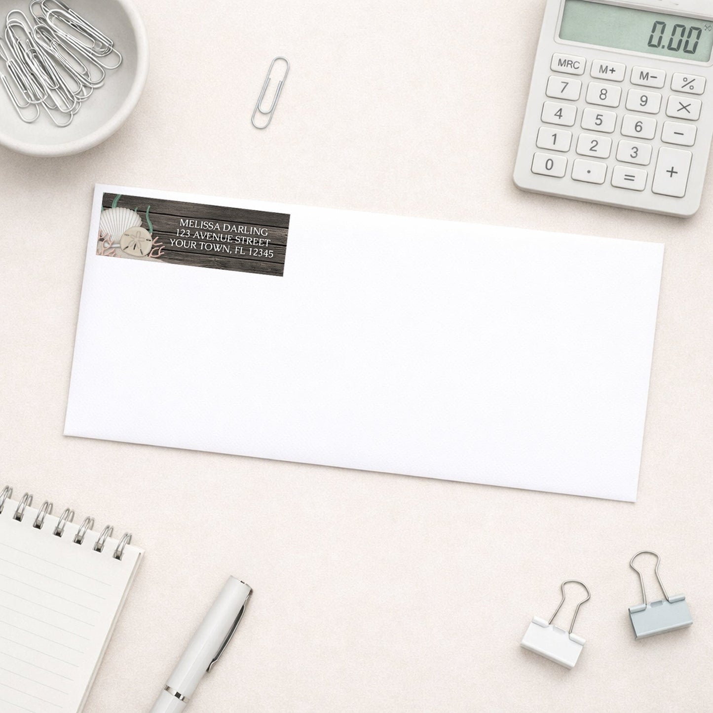 Rustic Beach Seashells and Wood Address Label shown on a white envelope with everyday office supplies