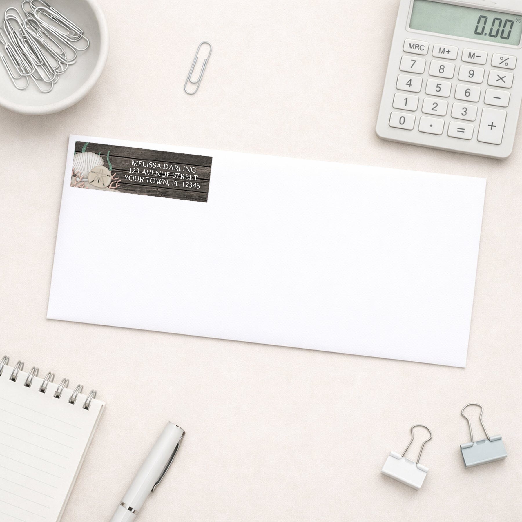 Rustic Beach Seashells and Wood Address Label shown on a white envelope with everyday office supplies
