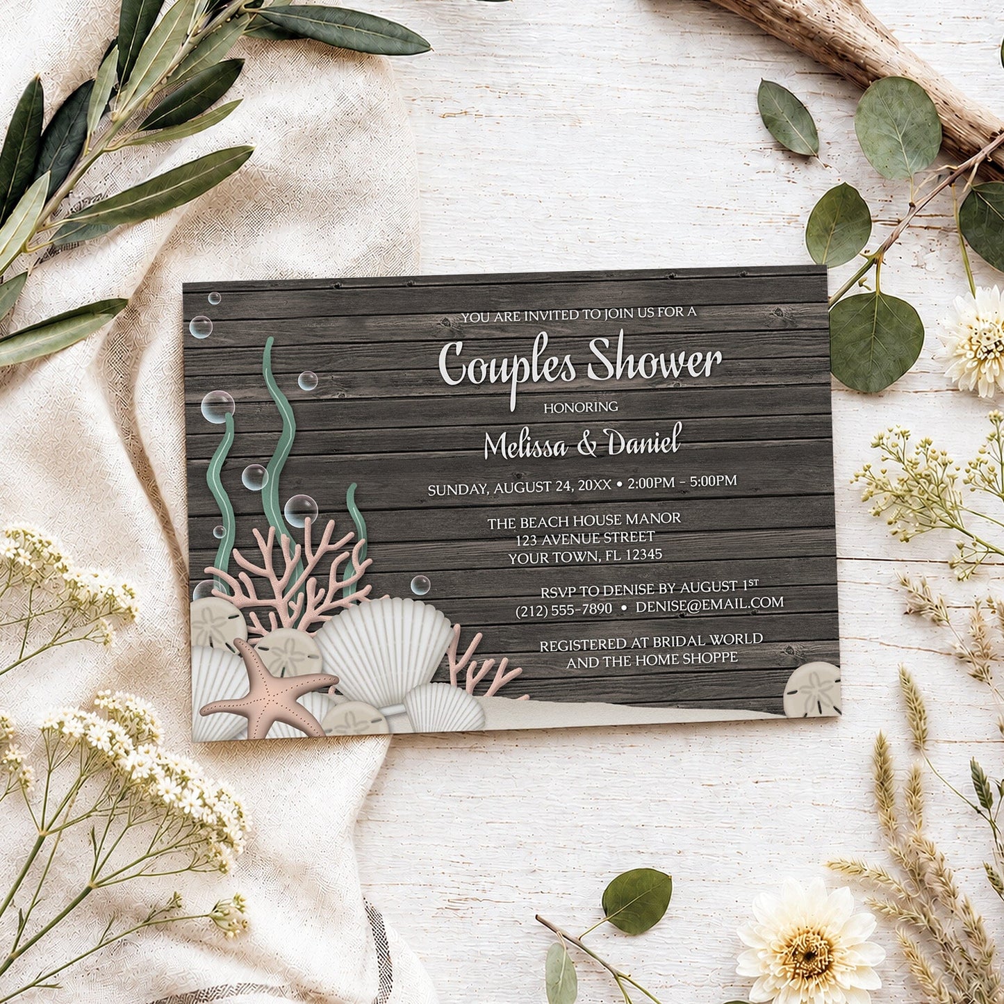 Rustic Beach Seashells and Wood Couples Shower Invitation shown on a light wooden surface with spring and summer plants.