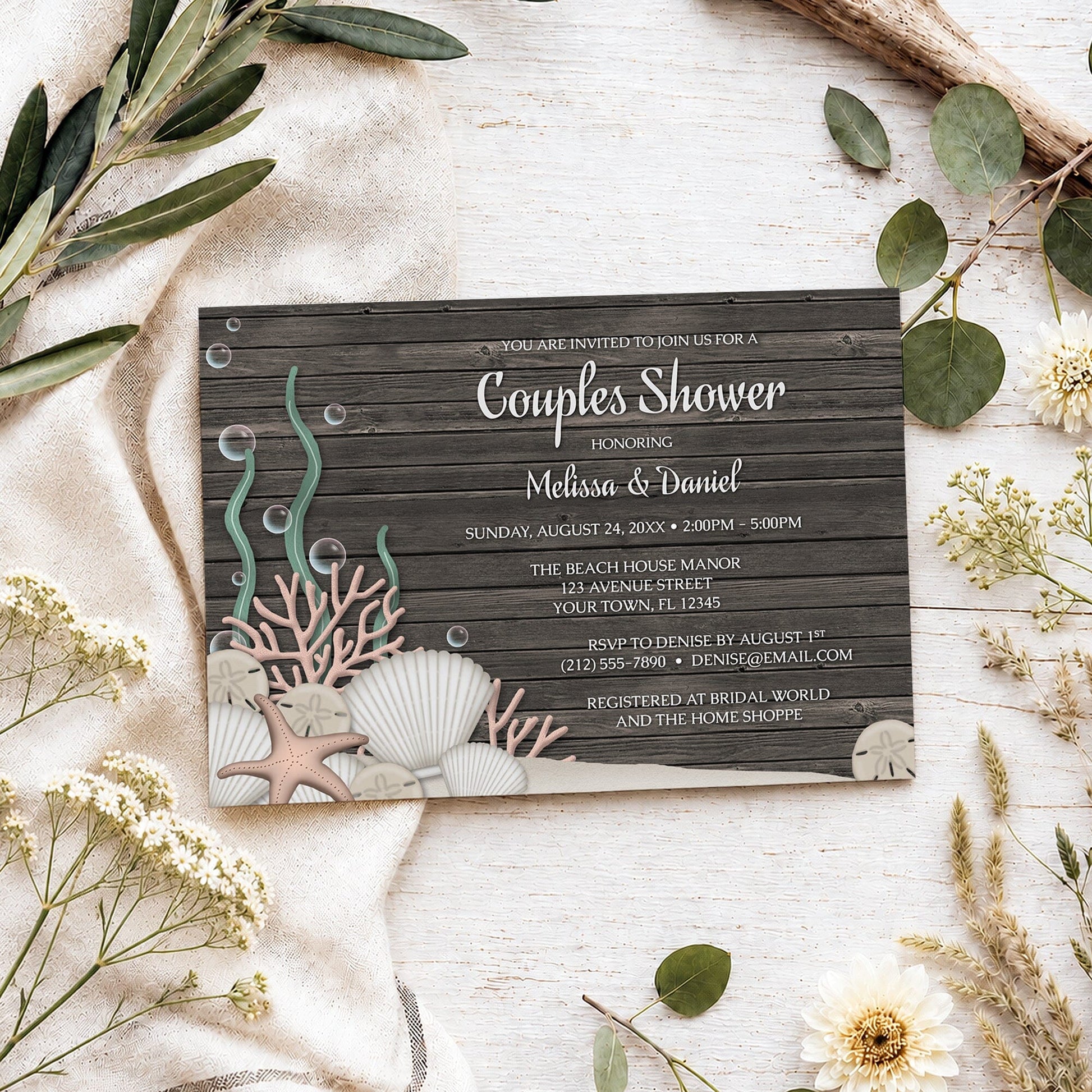 Rustic Beach Seashells and Wood Couples Shower Invitation shown on a light wooden surface with spring and summer plants.