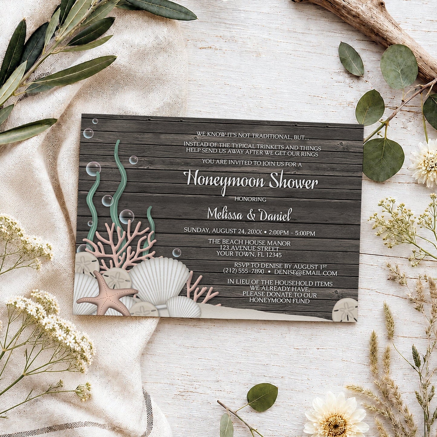 Rustic Beach Seashells and Wood Honeymoon Shower Invitation shown on a light wooden surface with summer plants.