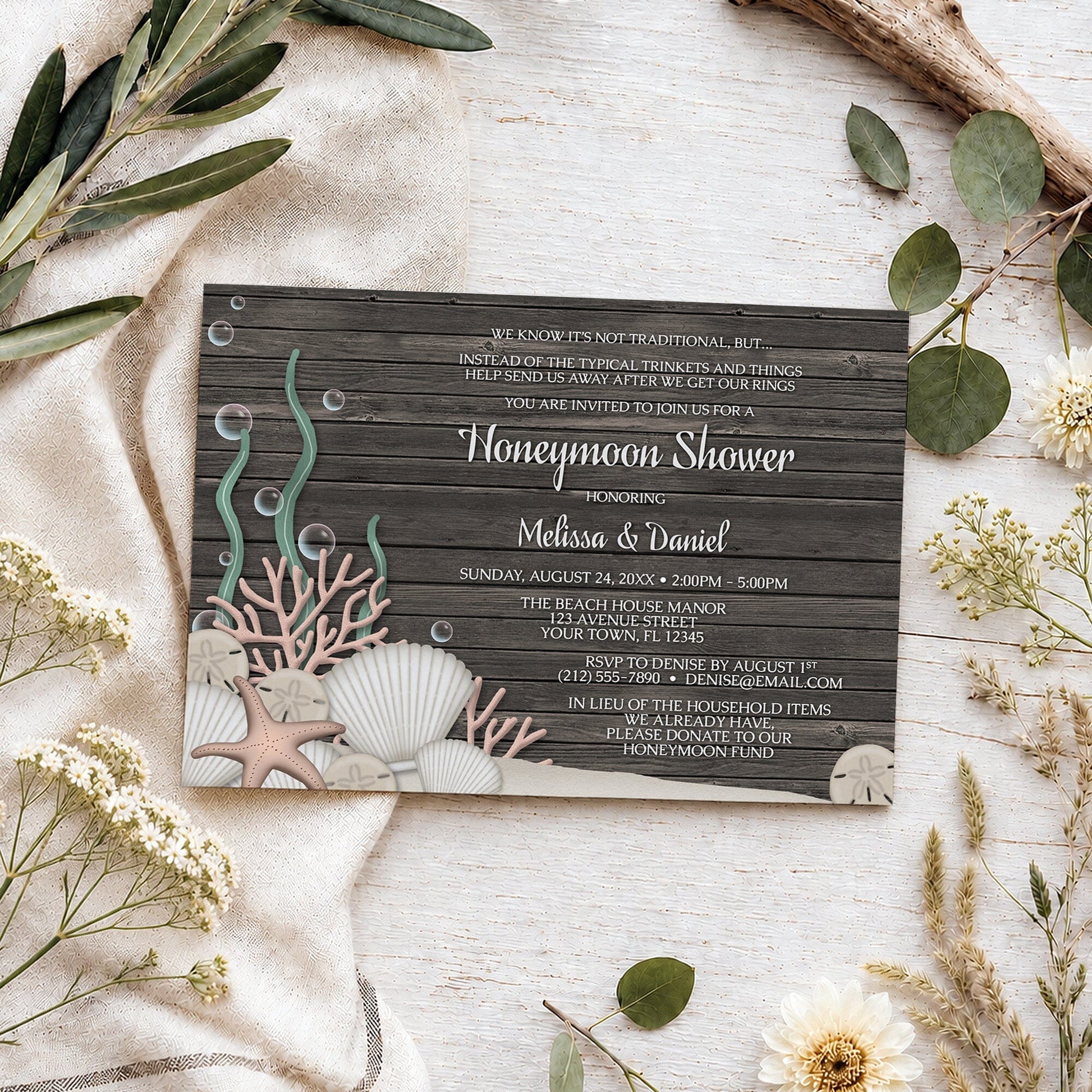 Rustic Beach Seashells and Wood Honeymoon Shower Invitation shown on a light wooden surface with summer plants.