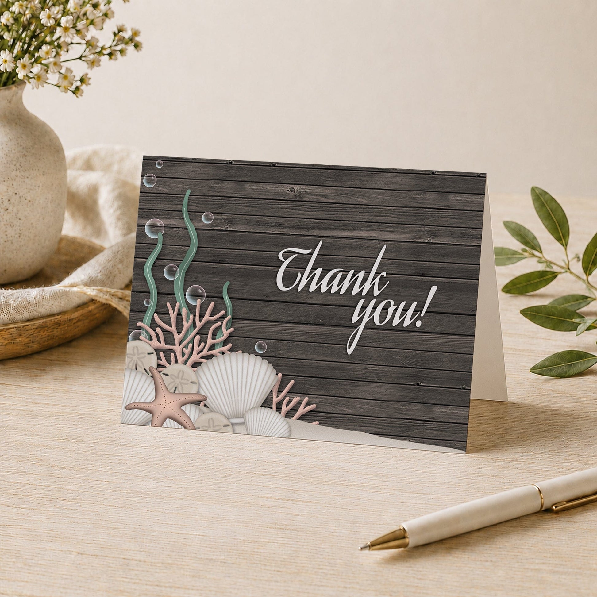 Rustic Beach Seashells and Wood Thank You Card shown on a tabletop with a vase, plants, and a pen.