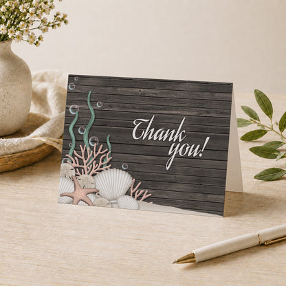 Rustic Beach Seashells and Wood Thank You Card shown on a tabletop with a vase, plants, and a pen.