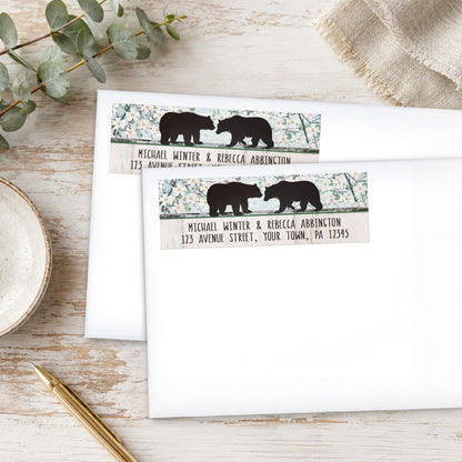 Rustic Bear Floral Wood Address Labels on white envelopes on a wooden surface with plants and a pen.