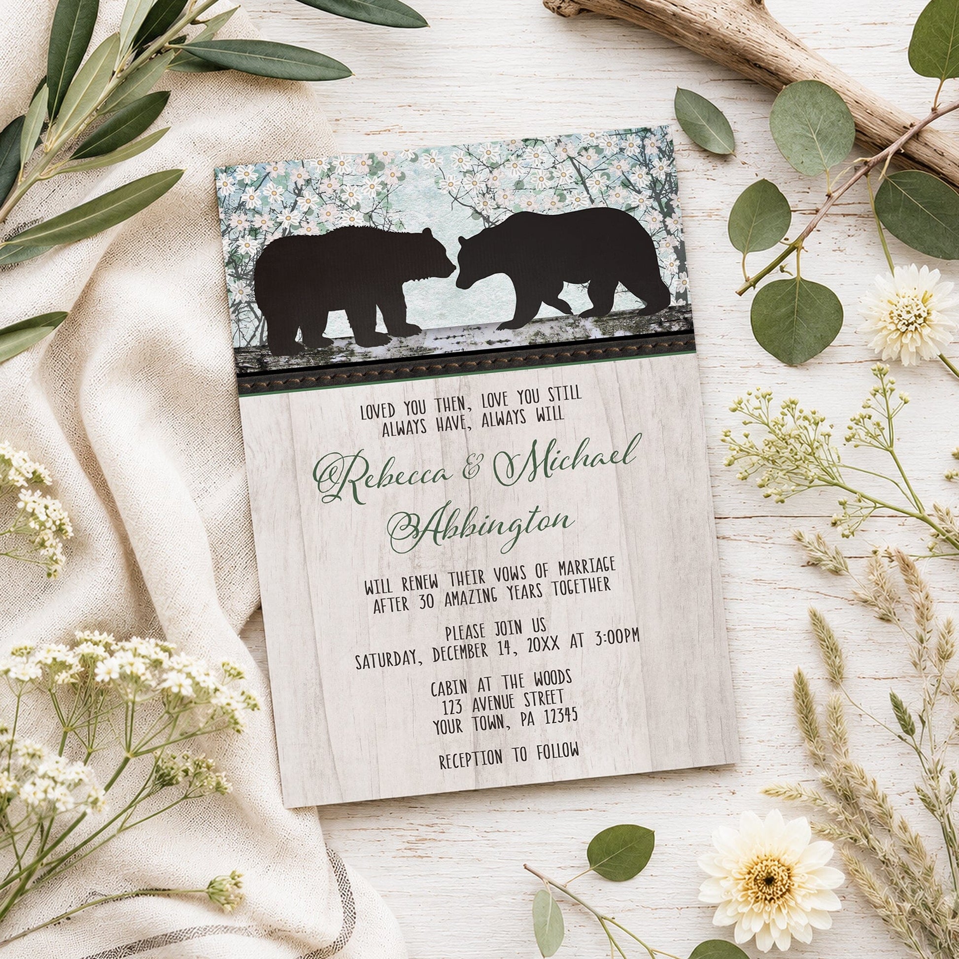 Rustic Bear Floral Wood Vow Renewal Invitation shown on a light wooden surface with spring and summer plants.