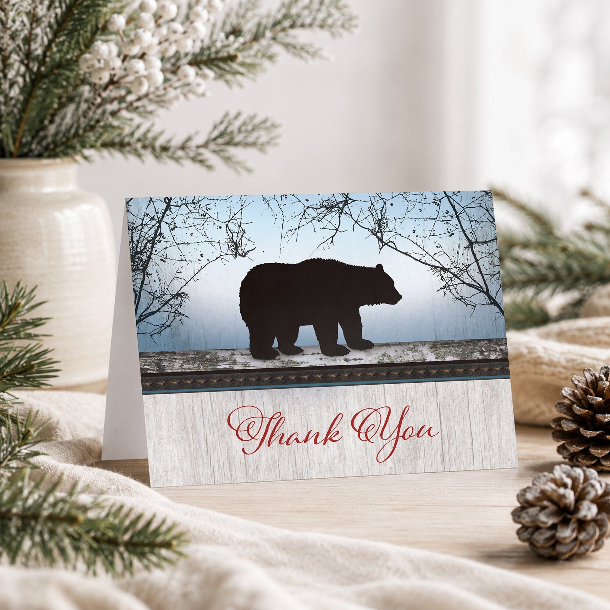 Rustic Bear Wood Red Blue Thank You Card shown on a tabletop with a vase, winter greenery, and pine cones.