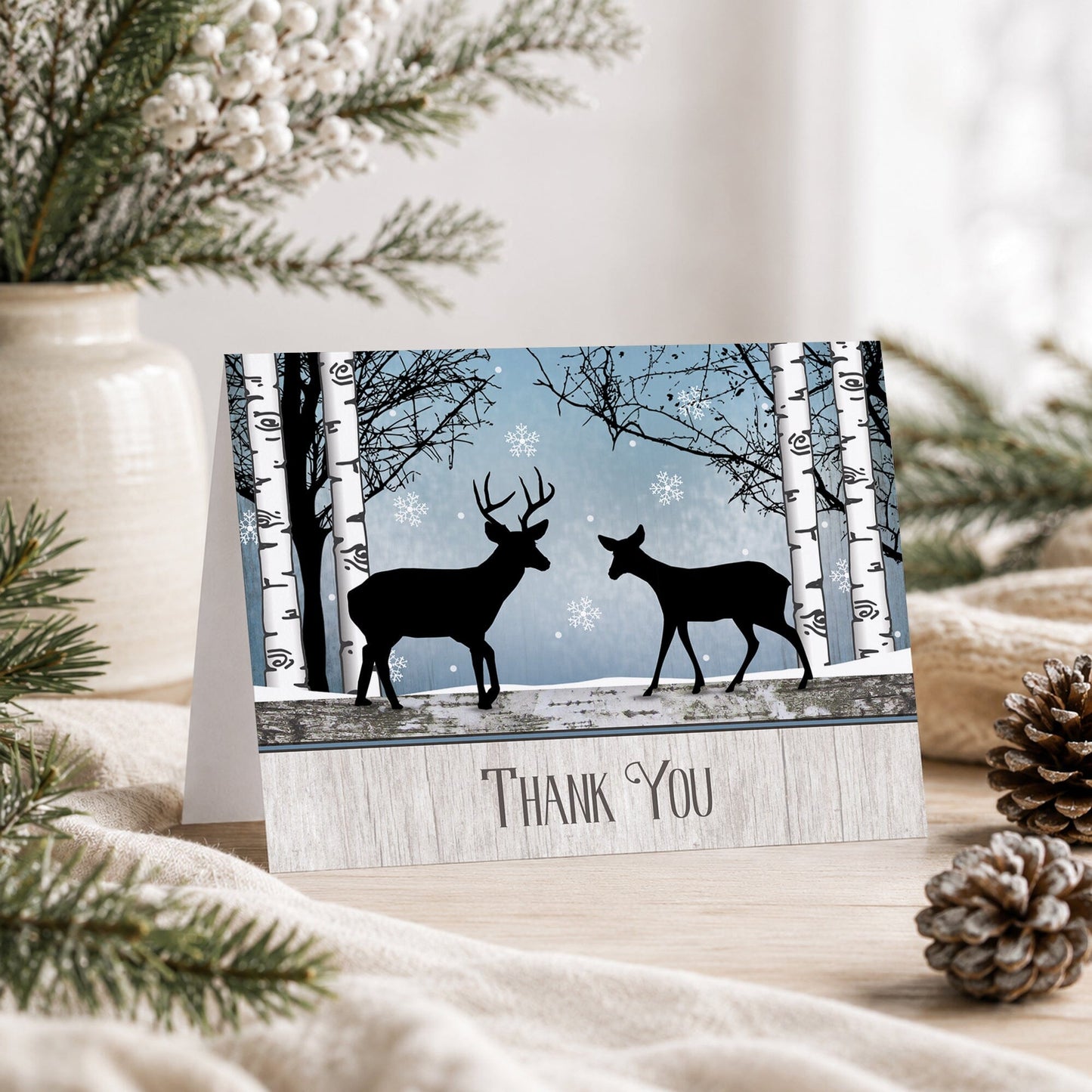 Rustic Blue Winter Deer Thank You Card shown on a tabletop with a vase, winter greenery, and pine cones.