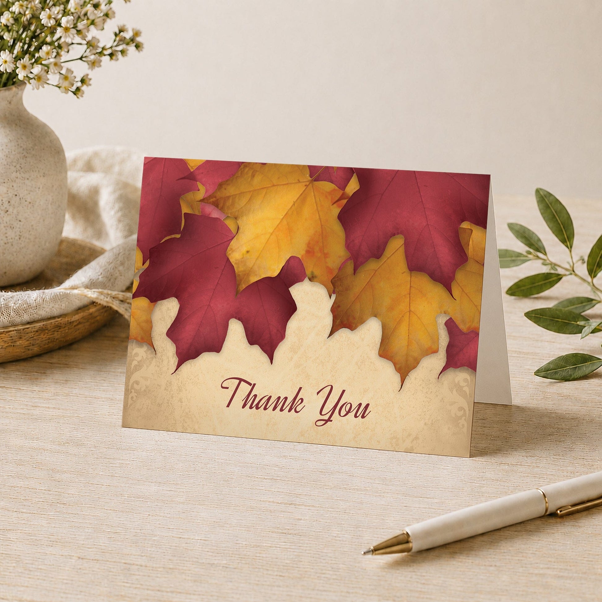 Rustic Burgundy Gold Autumn Thank You Card shown on a desk with a vase, plants, and a pen.