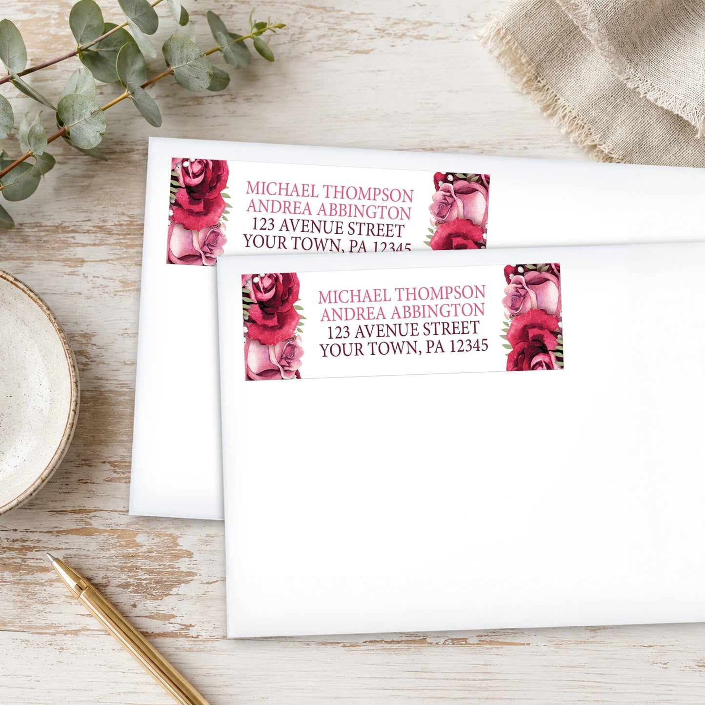 Rustic Burgundy Pink Rose White Address Labels, shown on white envelopes, on a wooden surface with eucalyptus leaves and a pen.