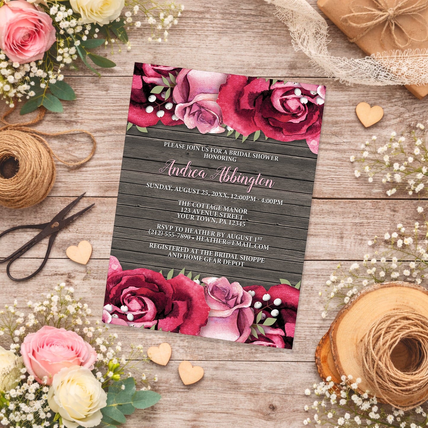 Rustic Burgundy Pink Rose Wood Bridal Shower Invitation shown on a wooden surface with spring and summer flowers, small wood hearts, and twine.