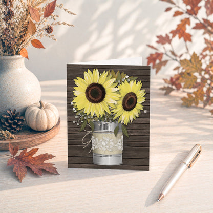 Rustic Burlap and Lace Tin Can Sunflower Note Card shown on a tabletop with fall leaves and autumn decor.