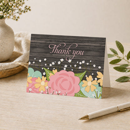 Rustic Floral Wood Baby's Breath Thank You Card shown on a desk with a vase, plants, and a pen.