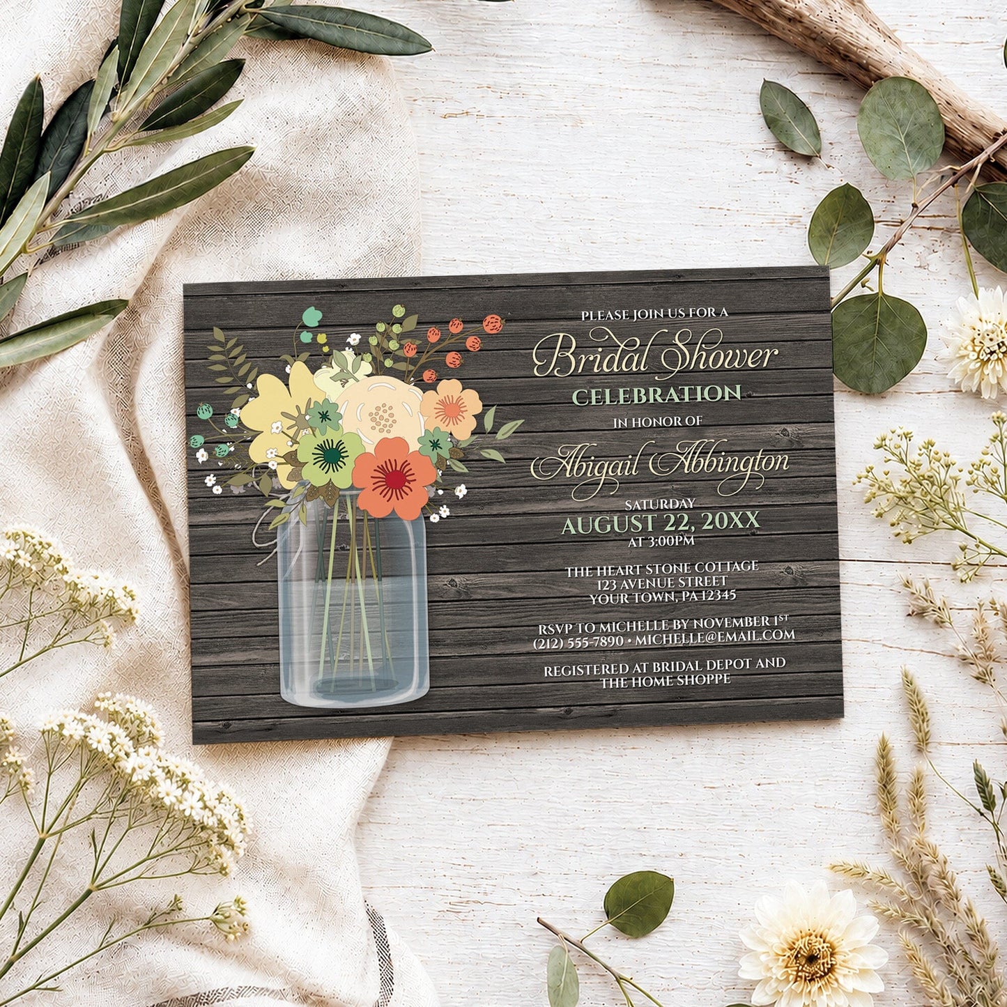 Rustic Floral Wood Mason Jar Bridal Shower Invitation shown on a light wooden surface with spring and summer plants.