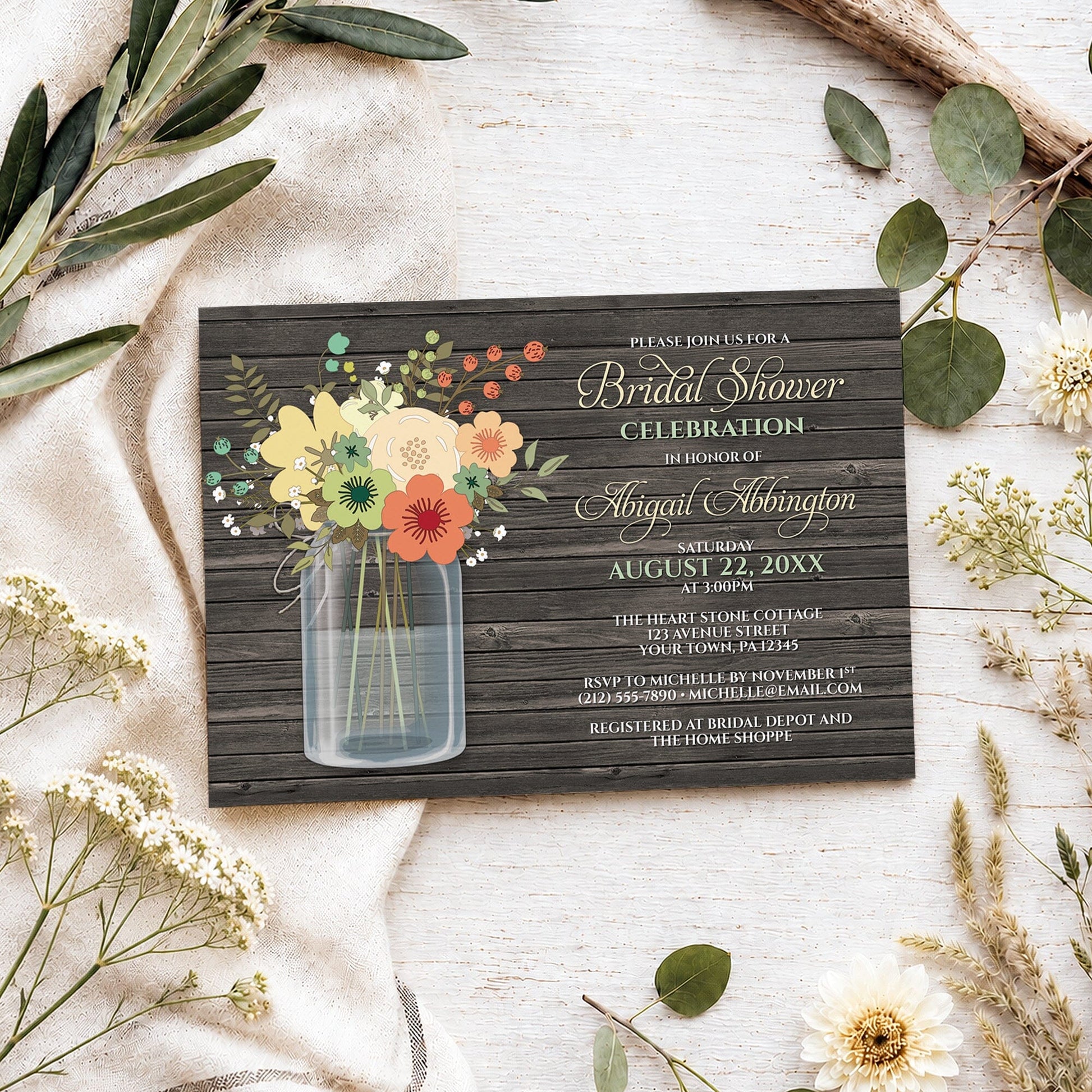 Rustic Floral Wood Mason Jar Bridal Shower Invitation shown on a light wooden surface with spring and summer plants.