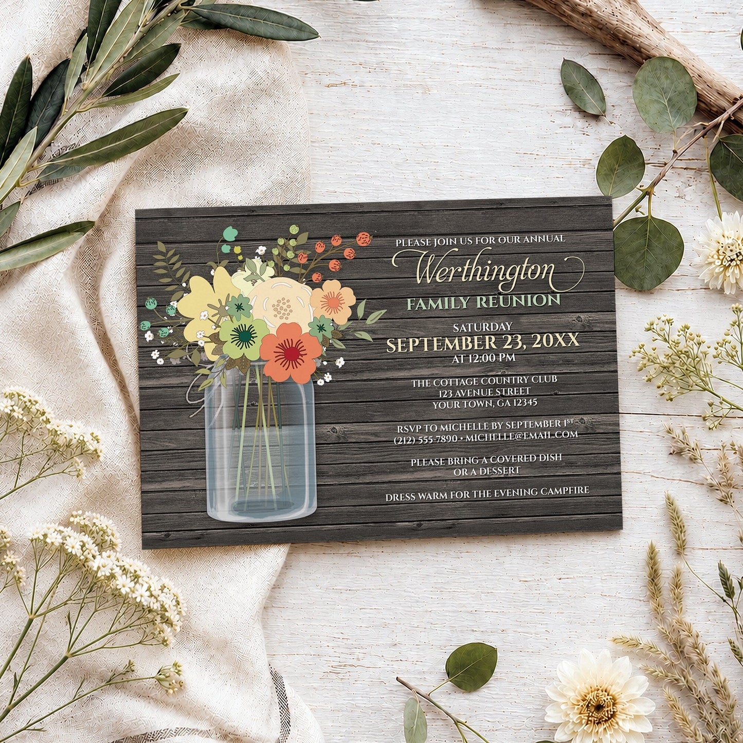 Rustic Floral Wood Mason Jar Family Reunion Invitation shown on a wooden surface with spring and summer plants.