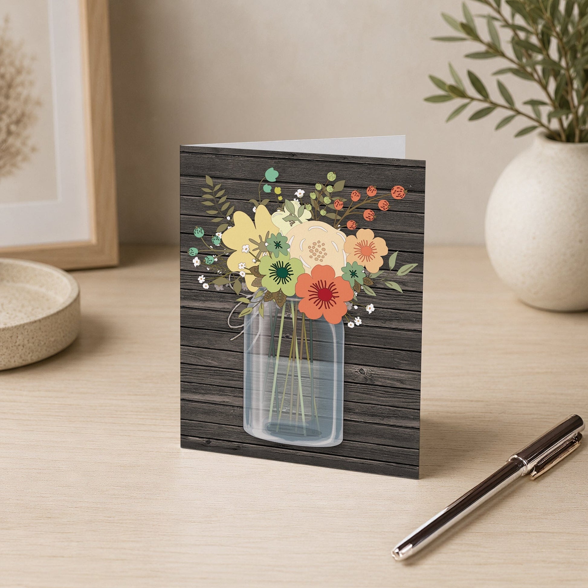 Rustic Floral Wood Mason Jar Note Card shown on a desk with a vase and pen.
