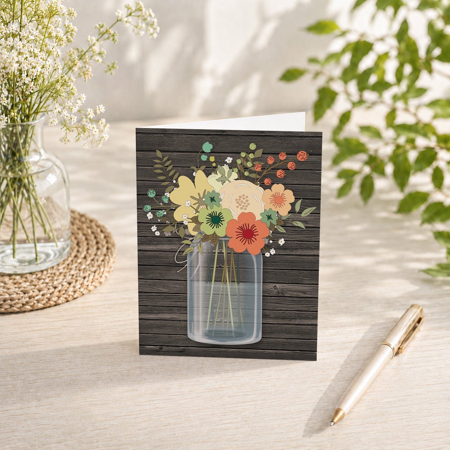 Rustic Floral Wood Mason Jar Note Card shown on a tabletop with a vase, spring and summer flowers, and a pen.