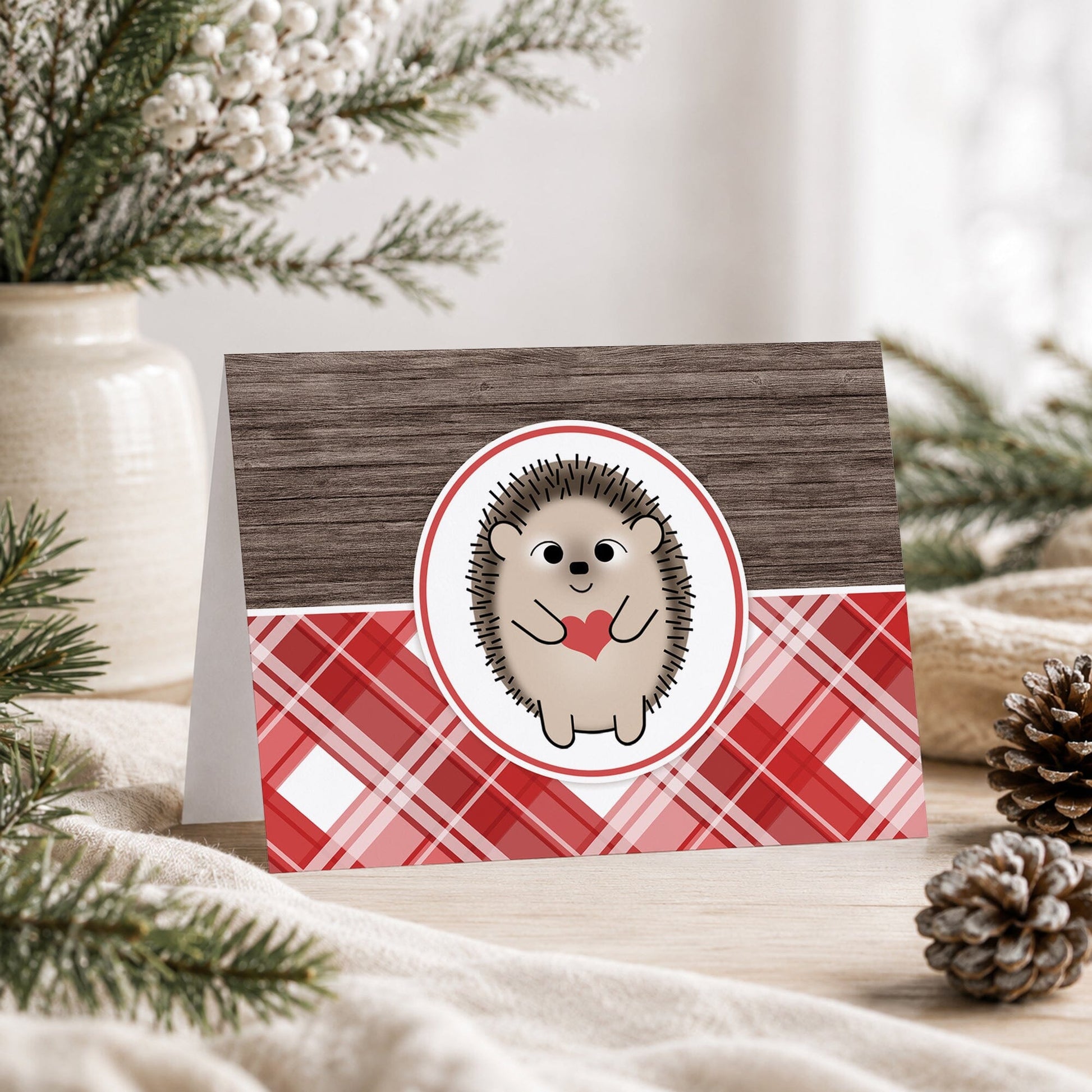 Rustic Hedgehog Heart Red Plaid Note Card shown on a tabletop with a vase, winter greenery, pine cones, and a blanket.