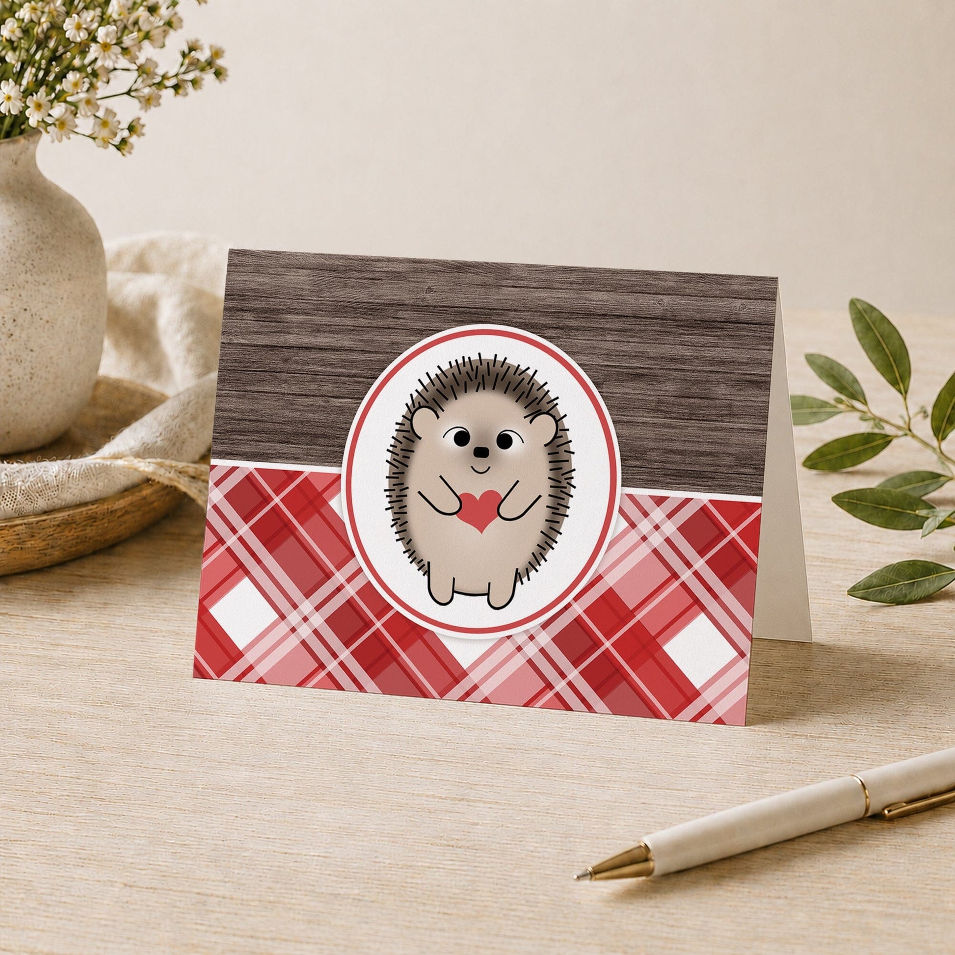 Rustic Hedgehog Heart Red Plaid Note Card shown on a tabletop with a vase, plants, and a pen.