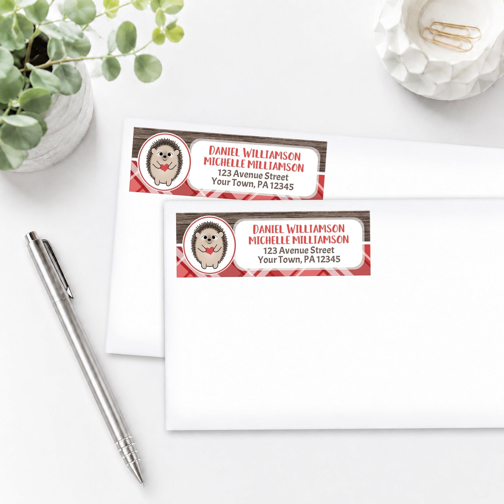 Rustic Hedgehog Red Plaid Address Labels, shown on white envelopes, on a white surface with a plant and a pen.