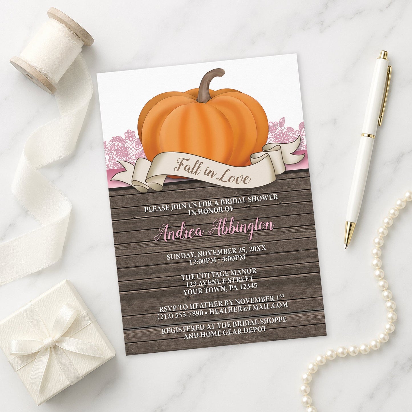 Rustic Orange Pink Pumpkin Fall in Love Bridal Shower Invitation on a marble surface with decorative items.
