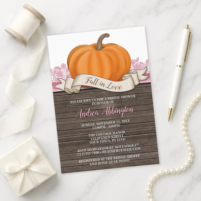 Rustic Orange Pink Pumpkin Fall in Love Bridal Shower Invitation on a marble surface with decorative items.