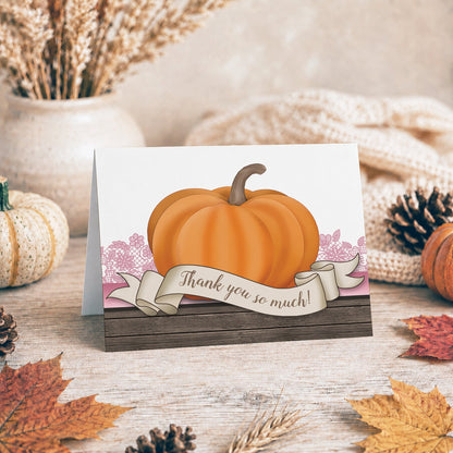 Rustic Orange Pink Pumpkin Thank You Card shown on a tabletop with a vase, fall leaves and autumn decor.