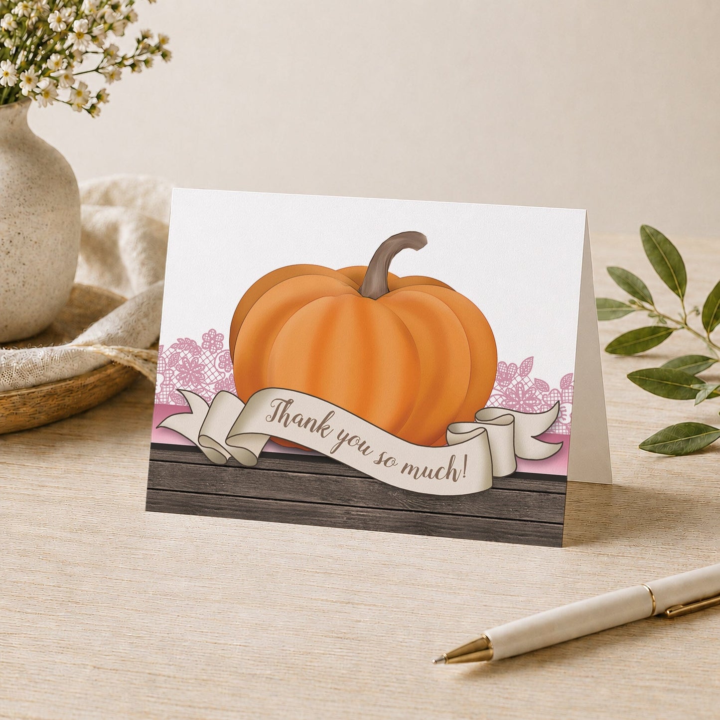 Rustic Orange Pink Pumpkin Thank You Card shown on a desk with a vase, plants, and a pen.