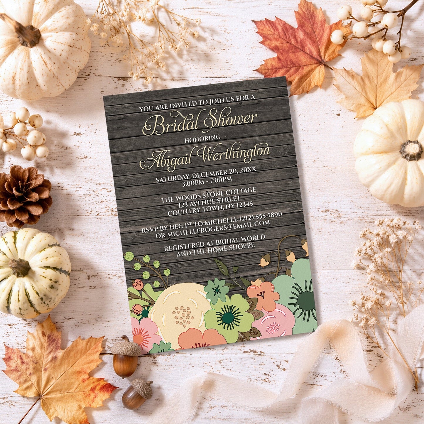 Rustic Orange Teal Floral Wood Bridal Shower Invitation shown on a rough light surface with fall leaves and autumn decor.