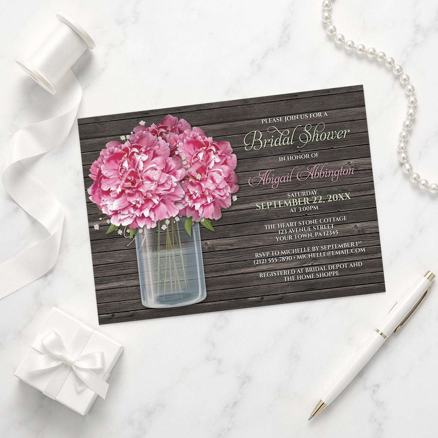 Rustic Peony Wood Mason Jar Bridal Shower Invitation on a marble surface with a white gift box, pen, ribbon, and pearls.