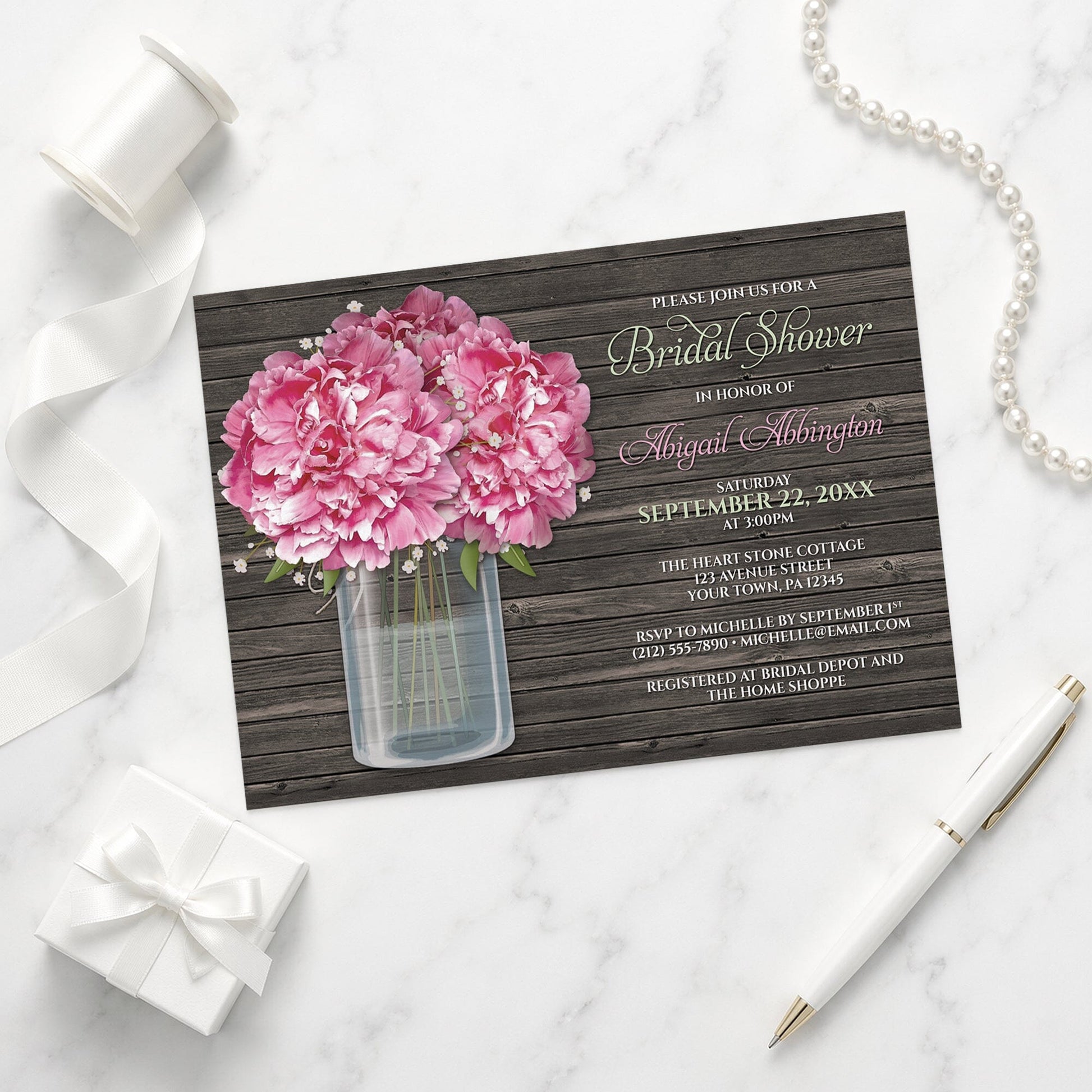 Rustic Peony Wood Mason Jar Bridal Shower Invitation on a marble surface with a white gift box, pen, ribbon, and pearls.