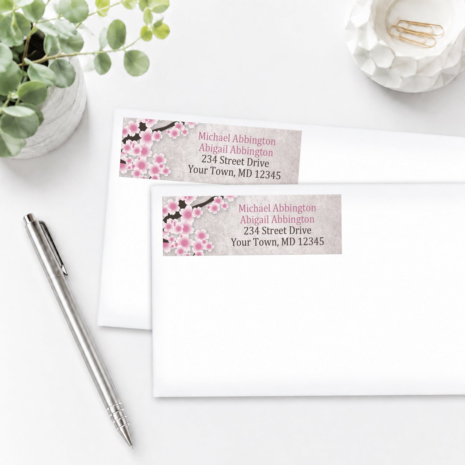 Rustic Pink Cherry Blossom Address Labels on white envelopes shown on a white surface with a pen and plant.