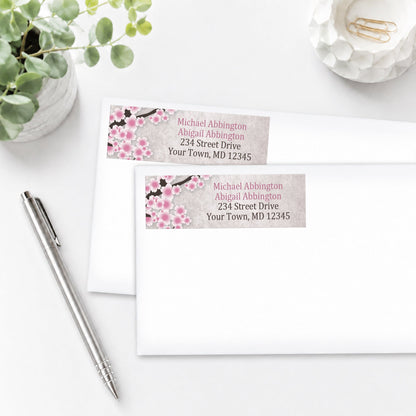 Rustic Pink Cherry Blossom Address Labels on white envelopes shown on a white surface with a pen and plant.