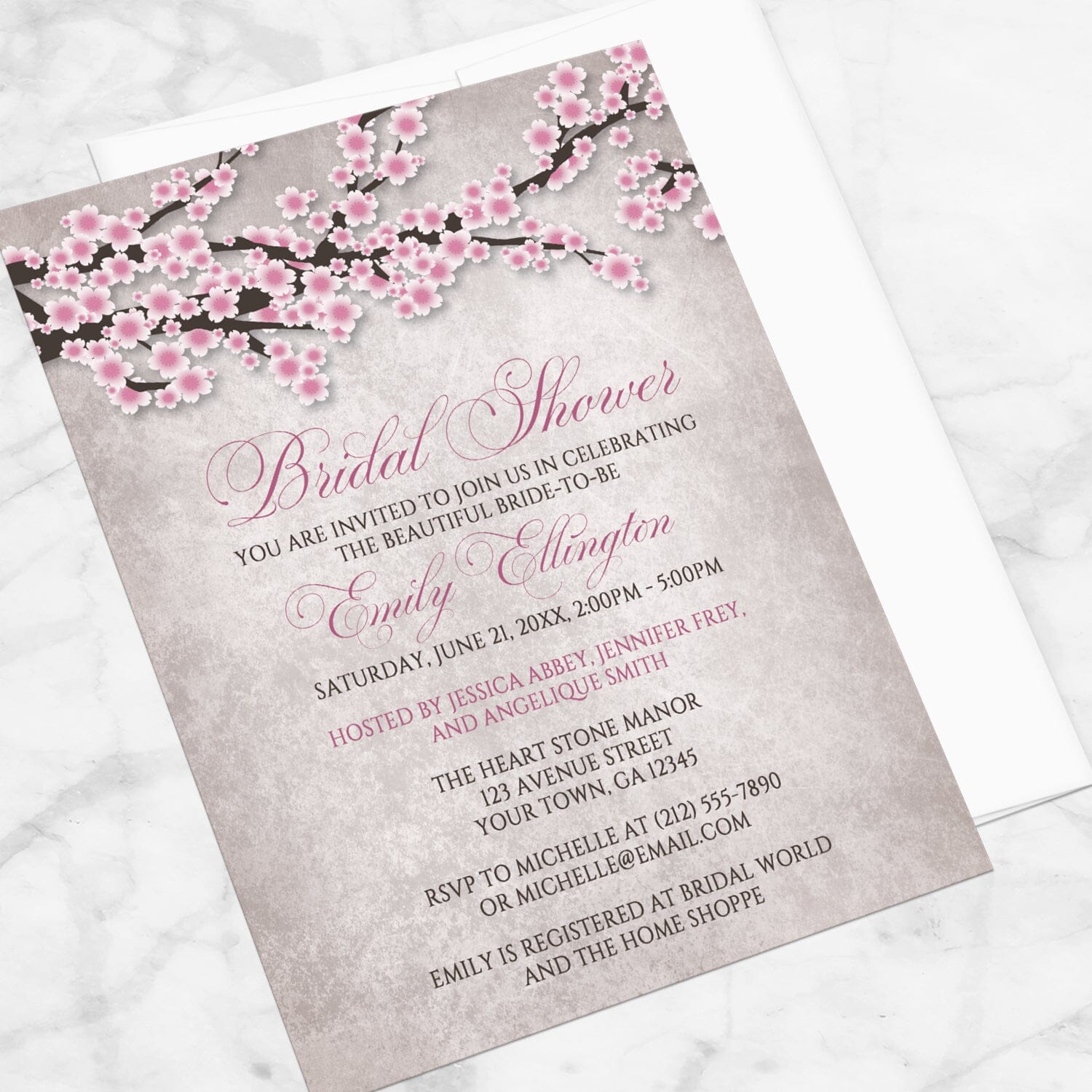 Bridal shower invitation with a rustic pink cherry blossom design, displayed at an angle with a white envelope on a marble surface