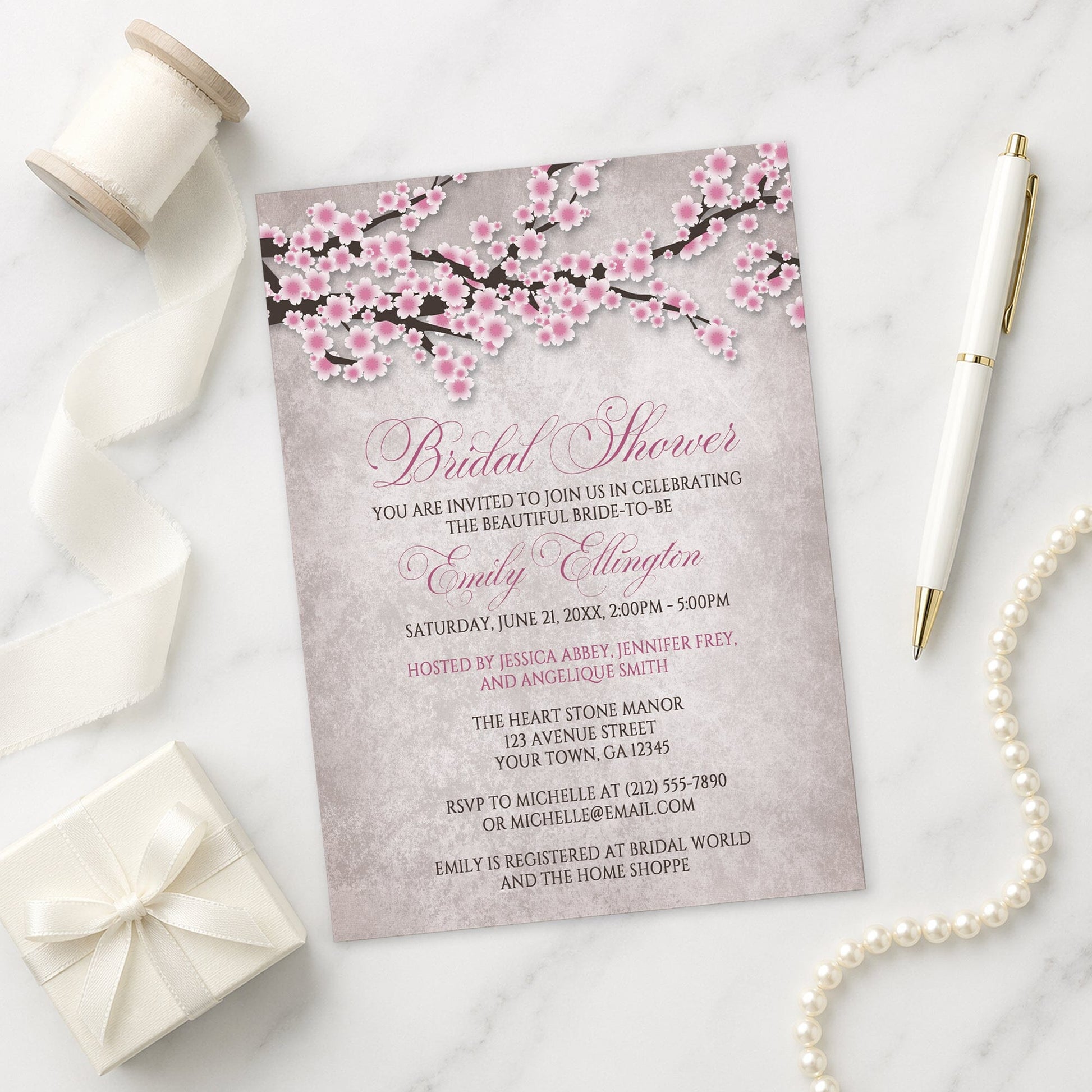 Rustic Pink Cherry Blossom Bridal Shower Invitation on a marble surface with a white gift box, pen, ribbon, and pearls.