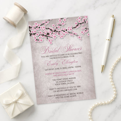 Rustic Pink Cherry Blossom Bridal Shower Invitation on a marble surface with a white gift box, pen, ribbon, and pearls.