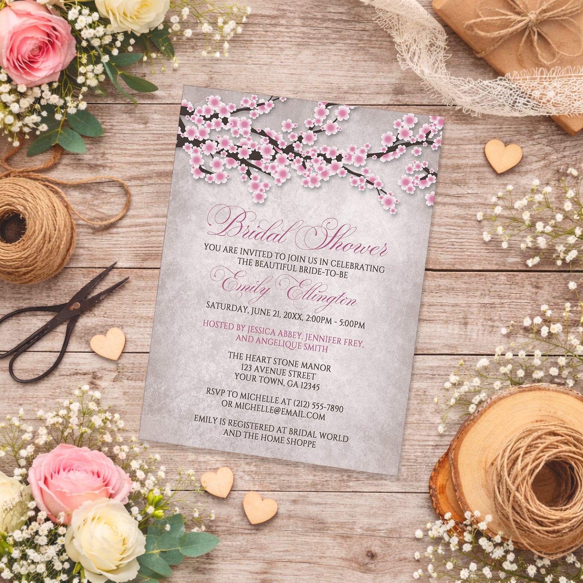 Rustic Pink Cherry Blossom Bridal Shower Invitation on a wooden surface with spring and summer flowers and twine.