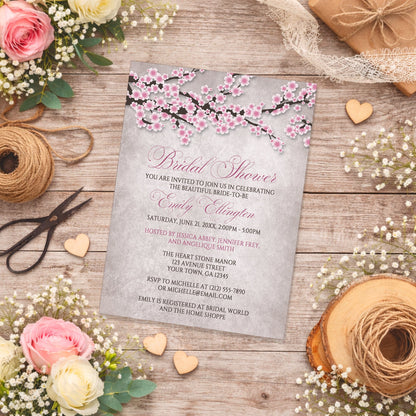 Rustic Pink Cherry Blossom Bridal Shower Invitation on a wooden surface with spring and summer flowers and twine.