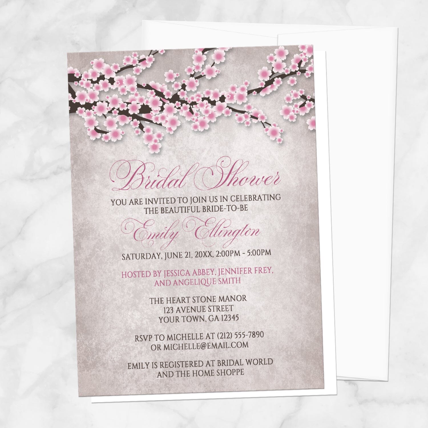 Bridal shower invitation with a rustic pink cherry blossom design, displayed with a white envelope on a marble surface