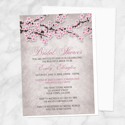Bridal shower invitation with a rustic pink cherry blossom design, displayed with a white envelope on a marble surface