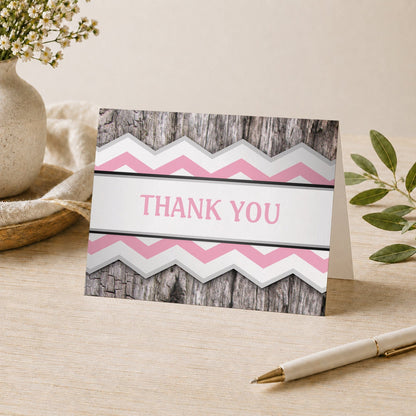 Rustic Pink Chevron and Wood Thank You Card shown on a desk with a vase, plants, and a pen.