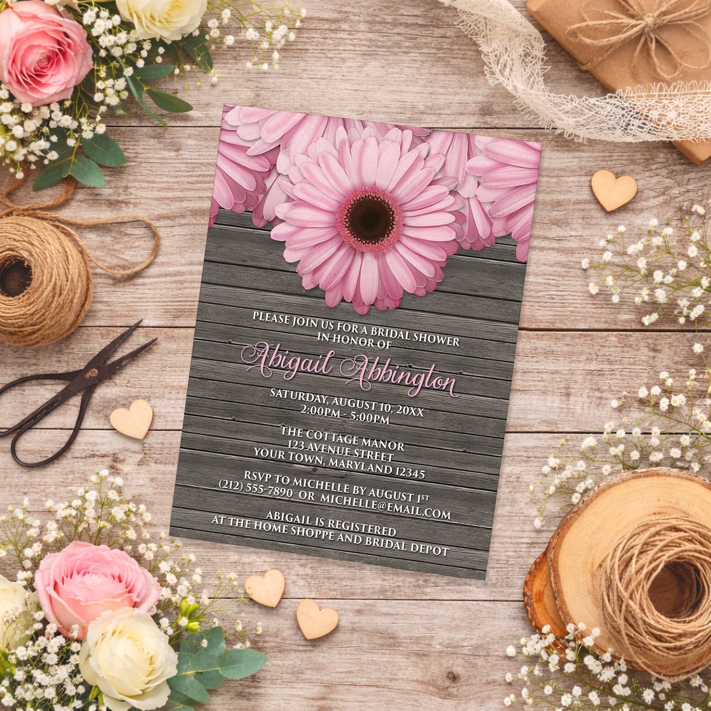 Rustic Pink Daisy Brown Wood Bridal Shower Invitation shown on a wooden surface with spring and summer flowers, small wood hearts, and twine.