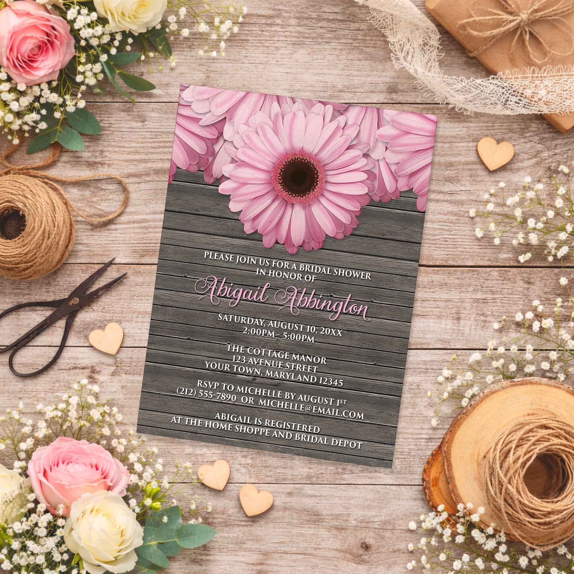 Rustic Pink Daisy Brown Wood Bridal Shower Invitation shown on a wooden surface with spring and summer flowers, small wood hearts, and twine.