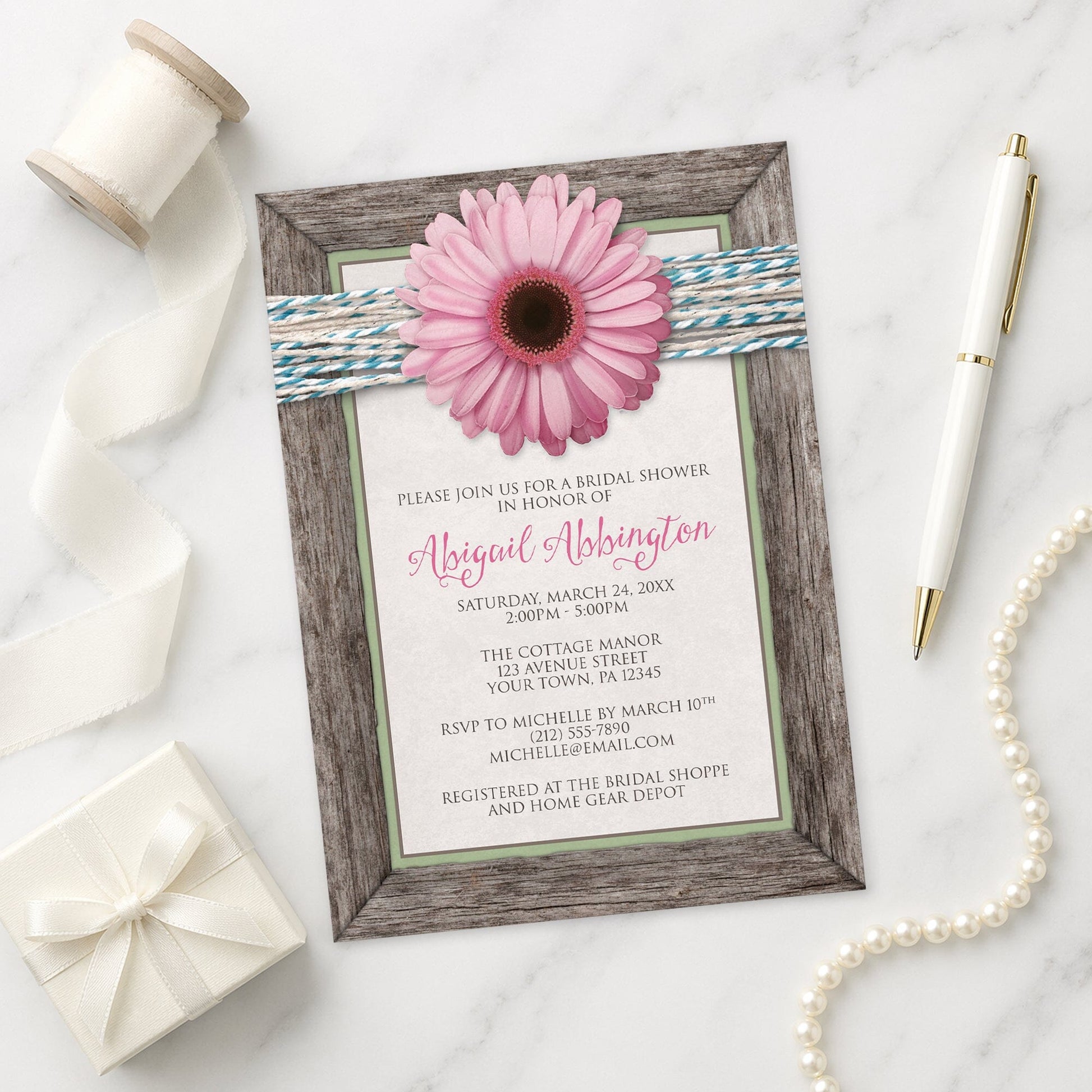 Rustic Pink Daisy Turquoise Wood Bridal Shower Invitation shown on a marble surface with a white gift box, pen, ribbon, and pearls.