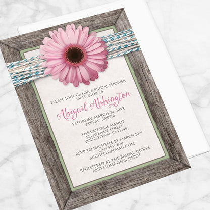 Rustic Pink Daisy Turquoise Wood Bridal Shower Invitation shown at an angle on a marble surface with a white envelope.