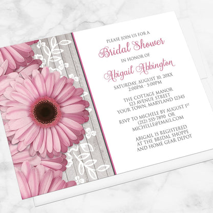 Rustic Pink Daisy Wood White Bridal Shower Invitation shown at an angle on a marble surface with a white envelope.
