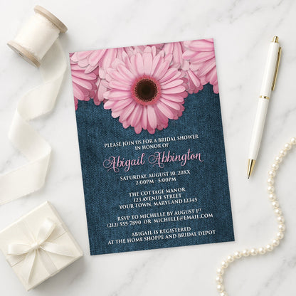 Rustic Pink Daisy and Denim Bridal Shower Invitation shown on a marble surface with a white gift box, pen, ribbon, and pearls.
